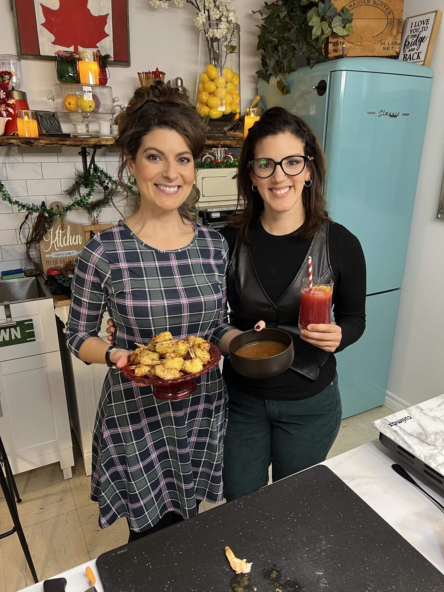 Maddie and Kiki, Canada's top female grill masters, holding food in their BBQ Bunker studio